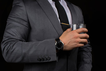 Hombre tomando whiskey con reloj lujoso