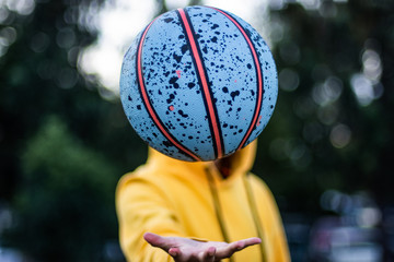 Unrecognizable person plays with a colorful basketball on his hand 