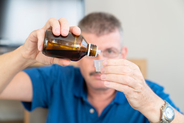 man pouring medicine into a measuring cup