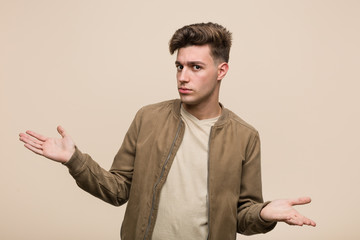 Young caucasian man wearing a brown jacket doubting between two options.