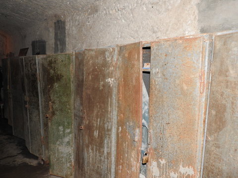 An abandoned prison in an underground bunker. A former Soviet cold war bomb shelter. The sealed door of the bunker. Pipes and valves. Low light condition. Bunker of fear and nightmares.