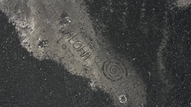 Aerial, 'aloha' and patterns drawn in black ground, top down rotating shot
