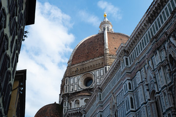 Florence's Santa Maria del Fiore Dome seen from the side with clouds and blue sky.