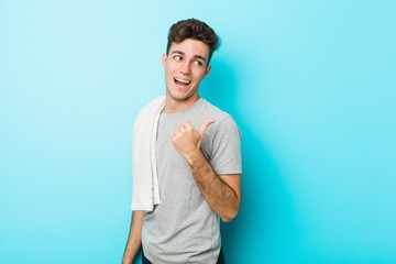 Young fitness teenager man points with thumb finger away, laughing and carefree.