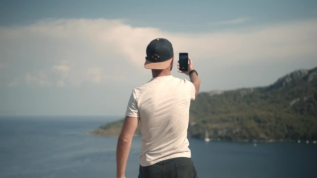 Guy Taking Selfie When Stay On Cliff.Man Take Photo On Beautiful Place In Turkey Coast.Man Takes Pictures On Smartphone On Seashore.Male Taking Self Photo And Answer To Video Call On Sea Cliff.