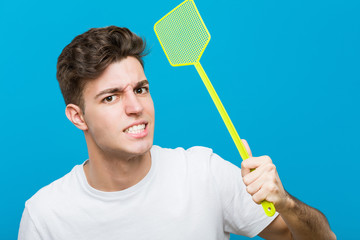 Teenager caucasian man using a flyswatter