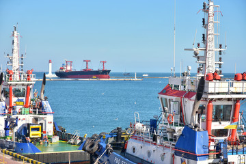 Odessa, Ukraine - October 2019. Cargo ship arrives at the port accompanied by a tugboat. Tugboats assisting container cargo ship to harbor. container ship vessel arrival to the port
