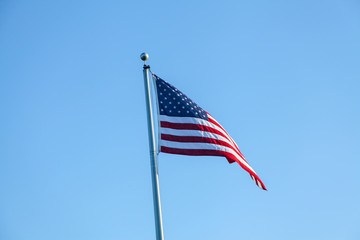 Flag of the United States of America, photograph in the wind, consists of 7 red bands and 6 white bands and a blue rectangle with 50 stars, symbolizing the states of the country.