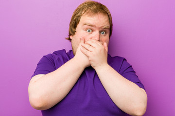 Young authentic redhead fat man shocked covering mouth with hands.