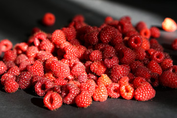 Beautiful red sunlit raspberry on black table