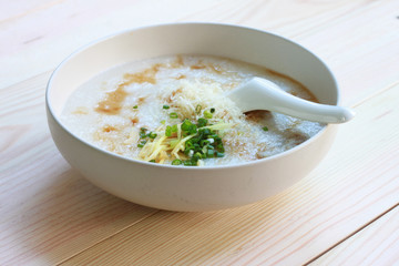 Congee, Rice porridge, Rice gruel, Rice soup, joke (China) on wooden table background, Top view, Selective and soft focus.