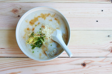 Congee, Rice porridge, Rice gruel, Rice soup, joke (China) on wooden table background, Top view, Selective and soft focus.