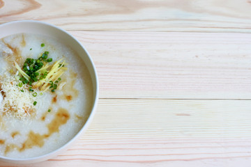 Congee, Rice porridge, Rice gruel, Rice soup, joke (China) on wooden table background, Top view, Selective and soft focus.