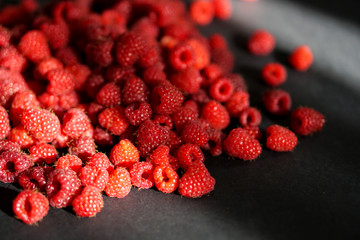 Scaterring of red raspberry on black background. Play of sunlights and shadows