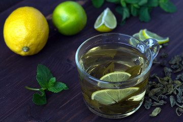 healthy lifestyle. cup of green tea with lemon and mint on wooden background