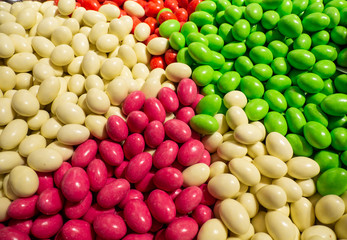 Close up of bowls filled with a large selection of different colored soft candies. Green, White, Red and pink candies
