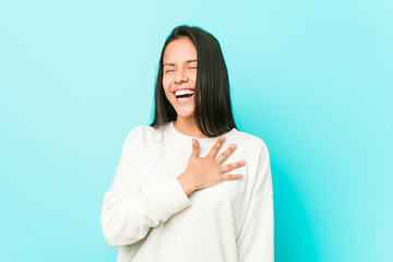 Young pretty hispanic woman laughs out loudly keeping hand on chest.