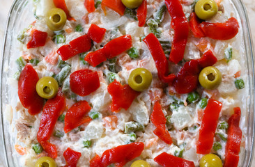 Primer plano de una ensalada a base de aceitunas, pimientos rojos y otras verduras con salsa mayonesa. (Ensaladilla rusa).