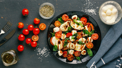 Italian caprese salad with chopped tomatoes, mozzarella cheese, basil, spices, balsamic vinegar and...