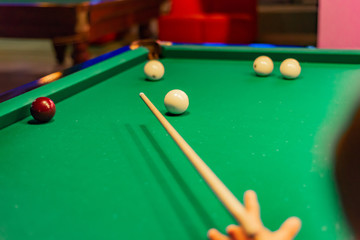 A man holds a billiard cue in his hands and hammer balls into a pocket.