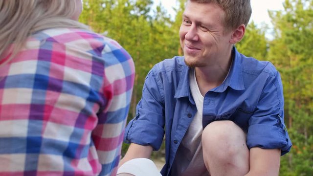 Over-the-shoulder shot of smiling man bandaging knee of his girlfriend and consoling her