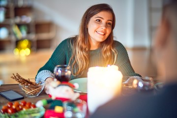 Young beautiful couple smiling happy and confident. Eating food celebrating christmas at home