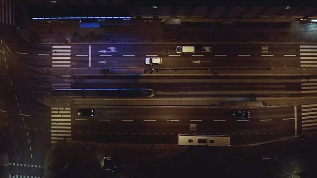 Aerial, top down, drone shot, of trams, a bus and traffic on a street, in downtown Helsinki, on a dark, autumn night, in Finland