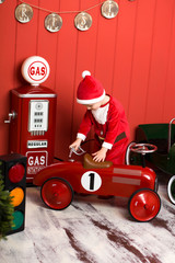 Little boy in santa claus costume rides a toy red car. Happy childhood. Christmas Eve.
