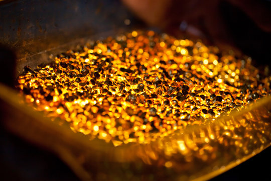closeup picture of many ingots of melt gold, hot shiny metal pieces glowing