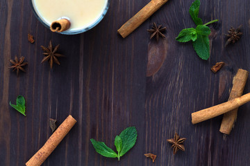 Cup of tea with milk with spices on wooden dark background. spices: anise stars and cinnamon with mint. christmas decoration. Healthy lifestyle. masala tea. top view with copy space in the centr