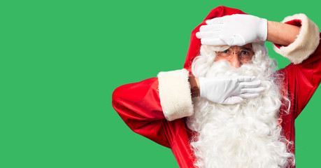Fototapeta na wymiar Middle age handsome man wearing Santa Claus costume and beard standing Smiling cheerful playing peek a boo with hands showing face. Surprised and exited