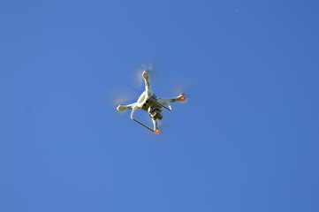 Quad drone with red lights on under a blue sky
