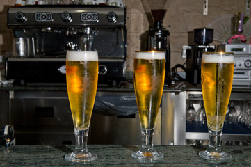 Three glasses of beer on top of a bar counter