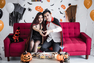 Couple in costume witch and dracula with celebrate Halloween party and put your hands together in...