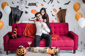 Couple in costume witch and dracula with celebrate Halloween party and drink wine together.