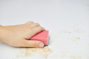 Cleaning kitchen table. Pink sponge in woman hand removes dirt, bread crumbs and leftovers....