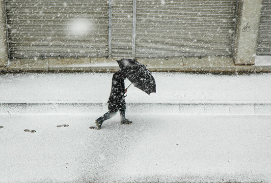 Hombre caminando bajo la nieve con paraguas