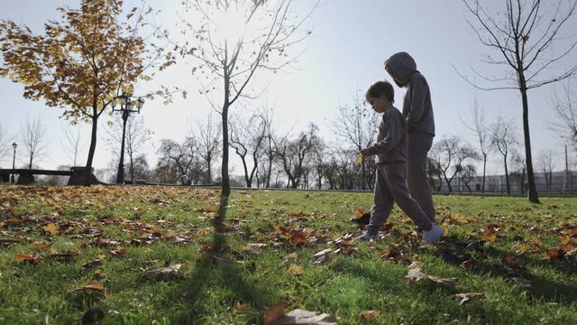 Mother and 6 year old boy walking in the park and enjoying the beautiful autumn nature. Happy family on autumn walk.