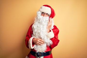 Middle age handsome man wearing Santa costume standing over isolated yellow background thinking looking tired and bored with depression problems with crossed arms.