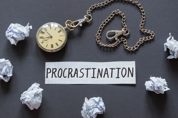 Word Procrastination and retro watch on the dark background.