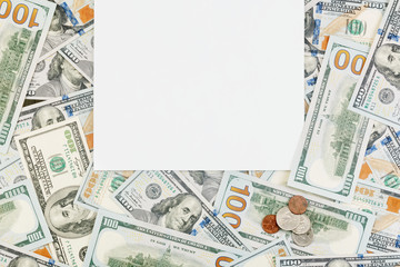 Blank white paper on background of dollar bills and coins. Financial concept with copy space for your text. Flat layout, top view.