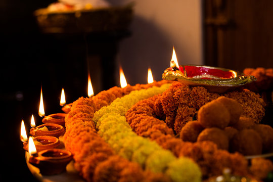 Happy Diwali - Clay Diya lamps lit during Dipavali, Hindu festival of lights celebration. Colorful traditional oil lamp diya and sweets on marble background