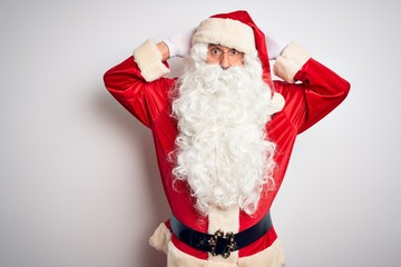 Middle age handsome man wearing Santa costume standing over isolated white background Crazy and scared with hands on head, afraid and surprised of shock with open mouth