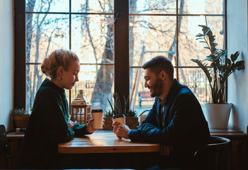 Handsome man and beautiful woman spend their time together while drinking coffee at cafeteria.