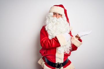 Middle age handsome man wearing Santa costume standing over isolated white background Showing palm hand and doing ok gesture with thumbs up, smiling happy and cheerful