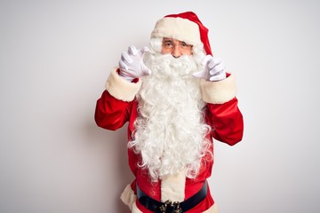 Middle age handsome man wearing Santa costume standing over isolated white background smiling funny doing claw gesture as cat, aggressive and sexy expression