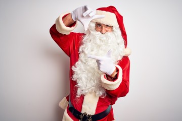 Middle age handsome man wearing Santa costume standing over isolated white background smiling making frame with hands and fingers with happy face. Creativity and photography concept.