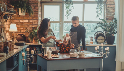 Small happy family are cooking together something tasty for Halloween party.