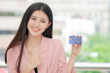 beautiful young Asian woman smiling while using credit card for online shopping