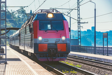 Fototapeta na wymiar Passenger train moves along the platform by Black sea coast. Sochi.